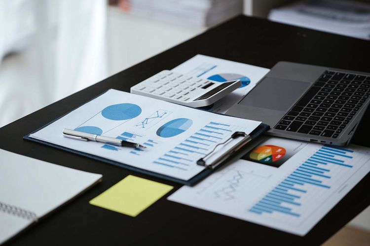 Desk with laptop, charts, and reports showing blue graphs and business analytics.