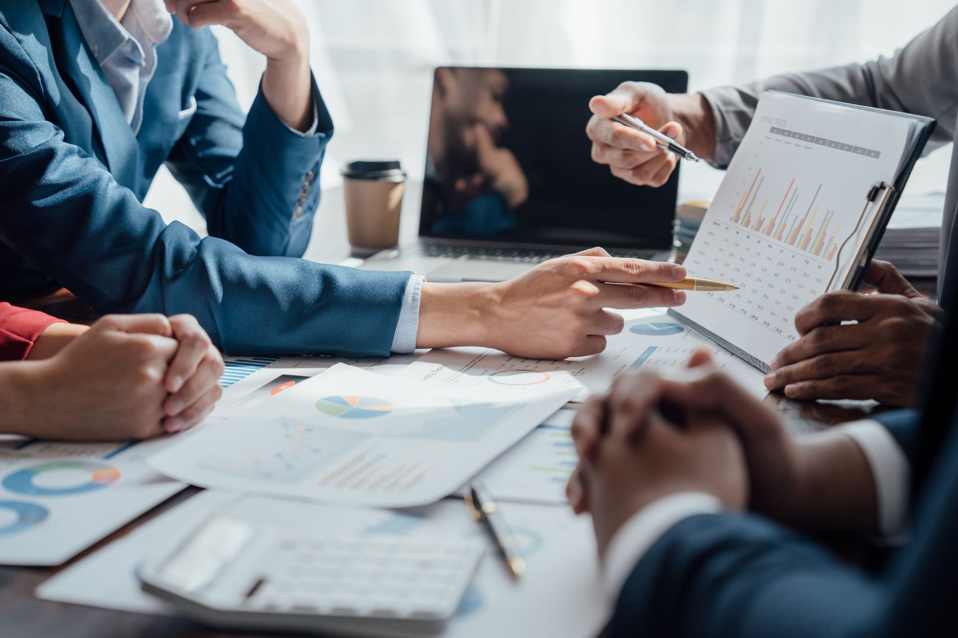 Business meeting with people reviewing charts and documents around a conference table