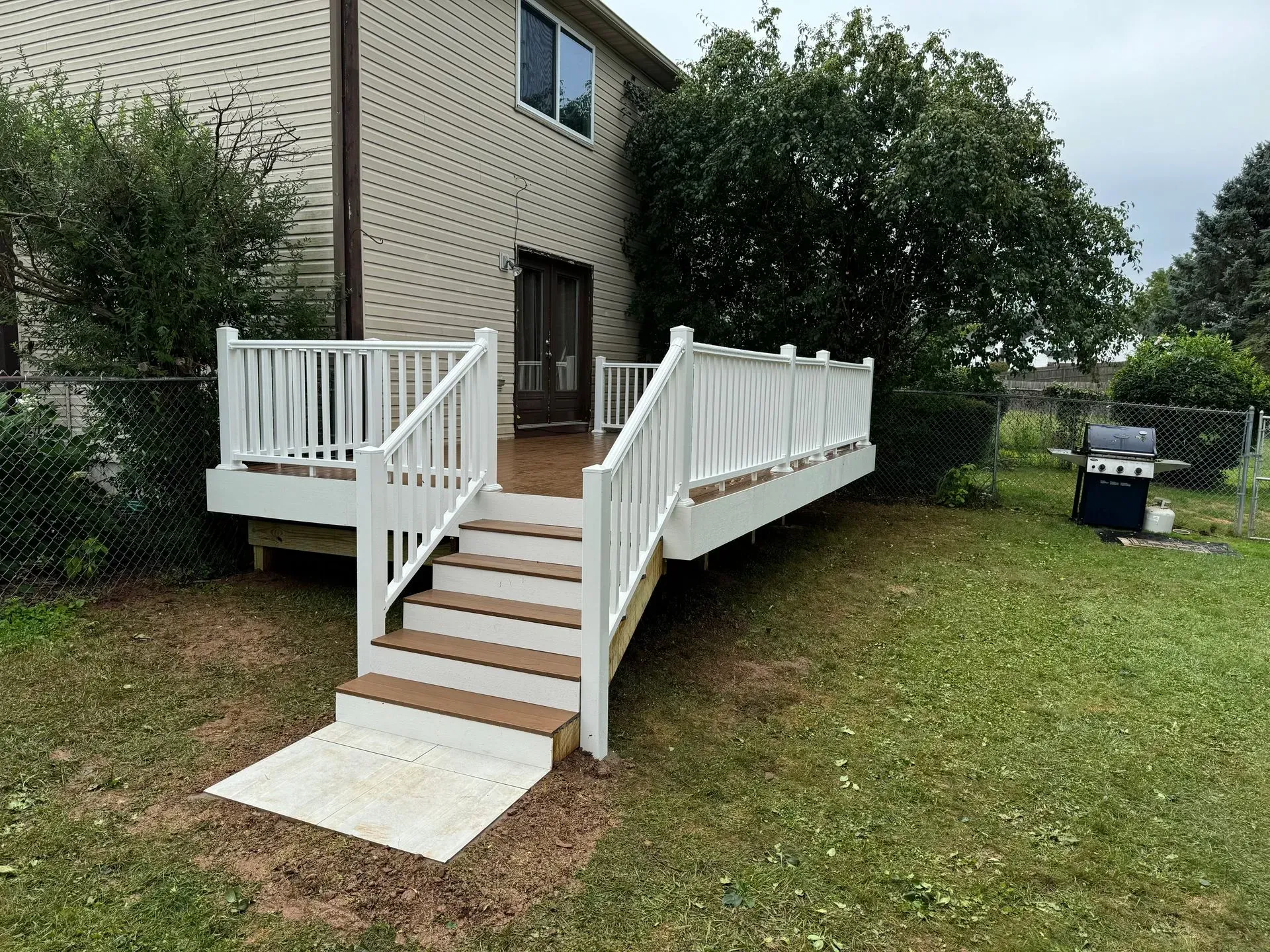 White wooden ramp and steps leading to a brick house entrance in a grassy yard.