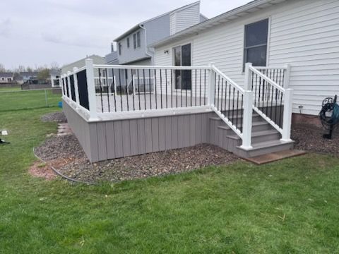 Raised white deck with stairs attached to a house, overlooking a grassy yard