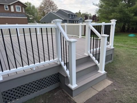 Back deck stairs with white railings and gray steps leading to a raised backyard deck