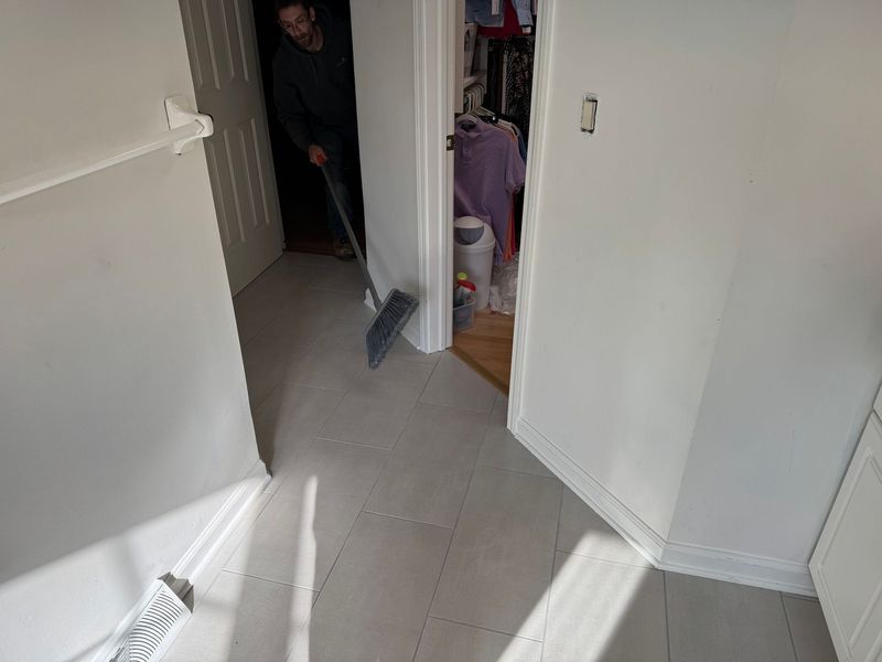 Hallway with open doors and bright sunlight on tiled floor; person stands in doorway ahead