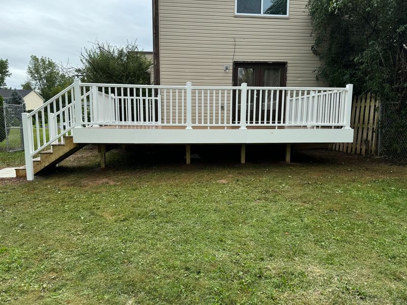 White wooden deck attached to a tan house, with stairs and railing overlooking a grassy yard