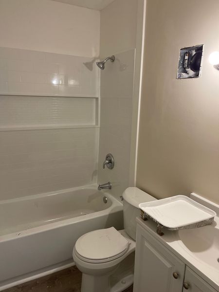 Small bathroom with tub-shower, toilet, sink, and white walls.