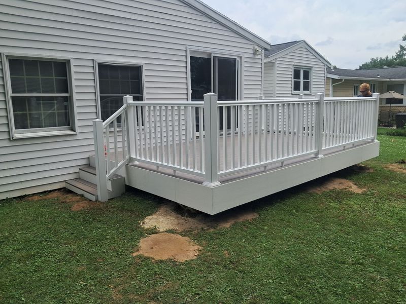 White wooden backyard deck attached to a house with steps and railing