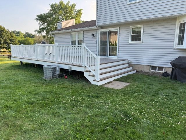 White wooden deck and stairs attached to the side of a house over a grassy yard