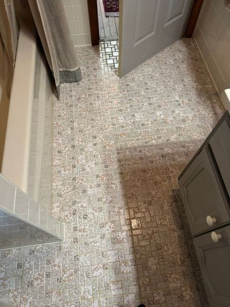 Small hallway with patterned vinyl floor, open door, and gray cabinets on the right.