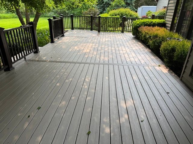 Wooden deck with black railings and green shrubs in a landscaped garden
