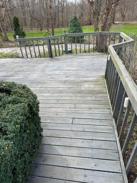 Wooden deck walkway with gray railings leading into a wooded yard