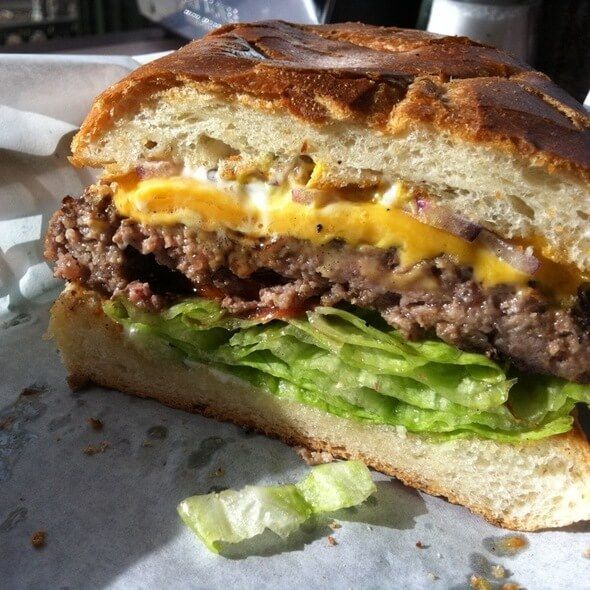 Close-up of a cheeseburger with lettuce and a toasted bun, cut open on a plate.