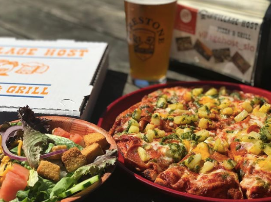 Pizza and salad on a restaurant table with a drink and menu in the background