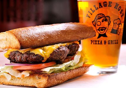 Cheeseburger with lettuce and tomato beside a beer glass on a restaurant table