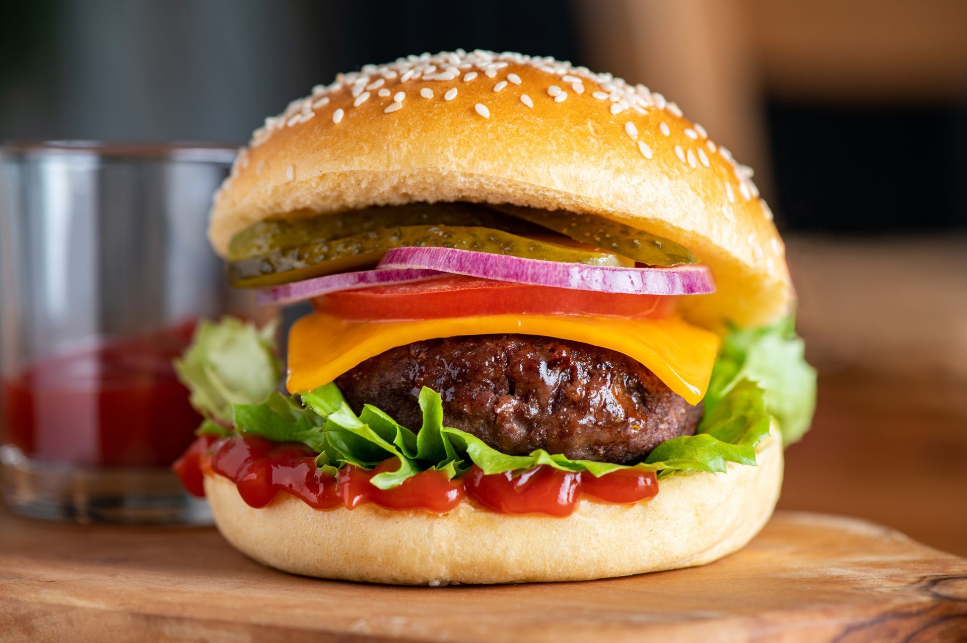 A close up of a hamburger on a wooden cutting board.