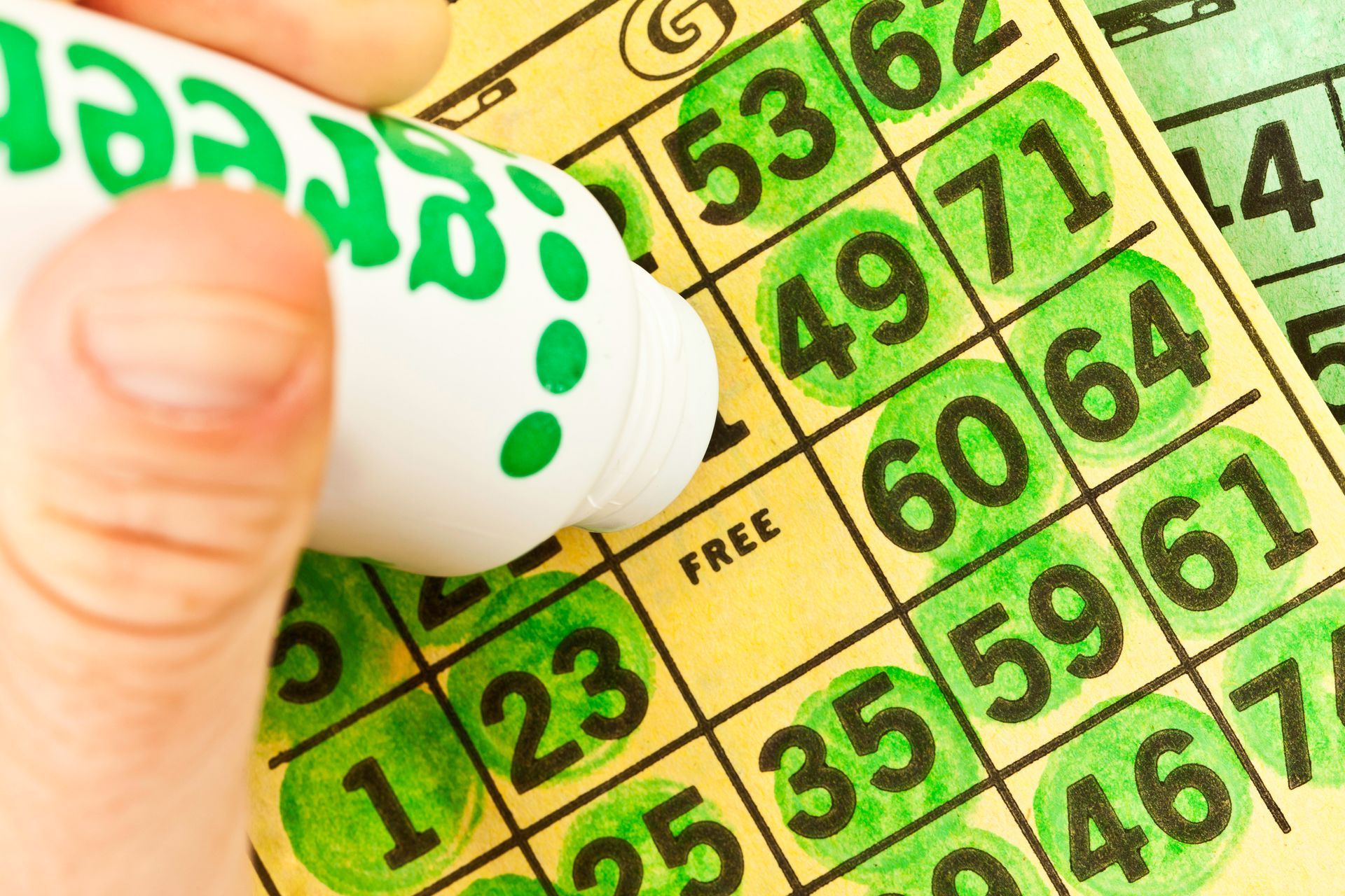 A person is writing on a bingo card with a marker.