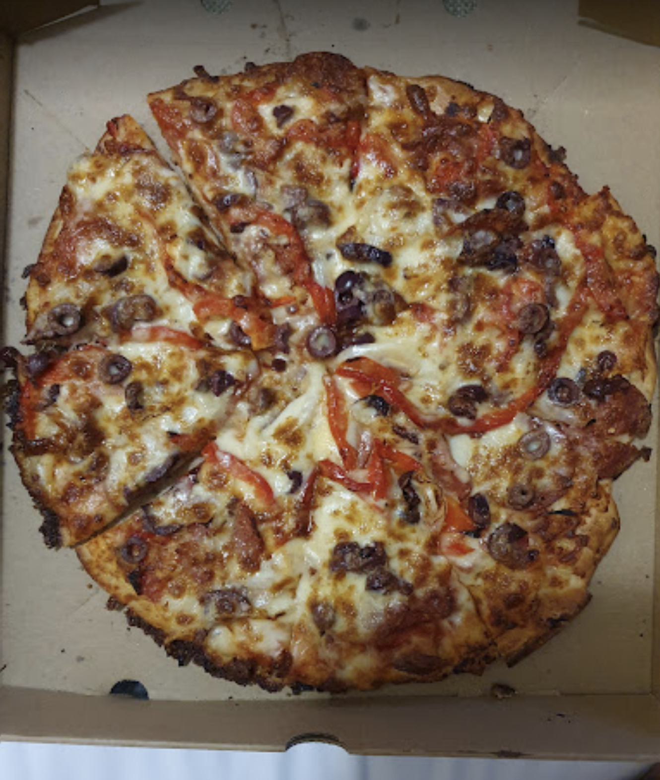 A pizza with a lot of toppings is in a cardboard box — Bella M Pizzas in Bundaberg North, QLD