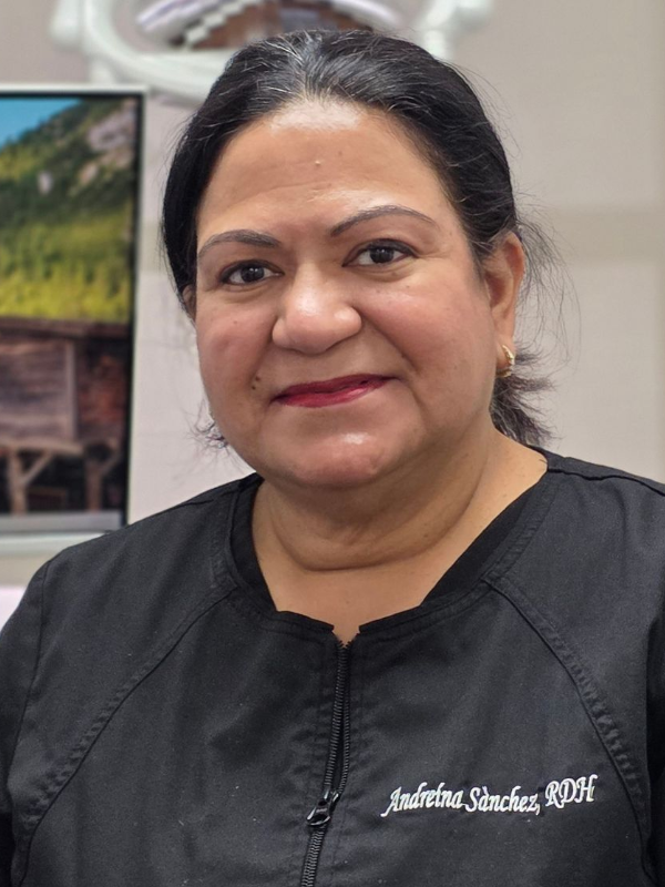 Portrait of a woman in a black top, smiling indoors against a softly blurred background