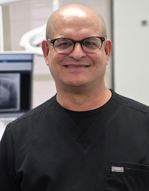 Smiling person in black shirt and glasses standing in a medical office