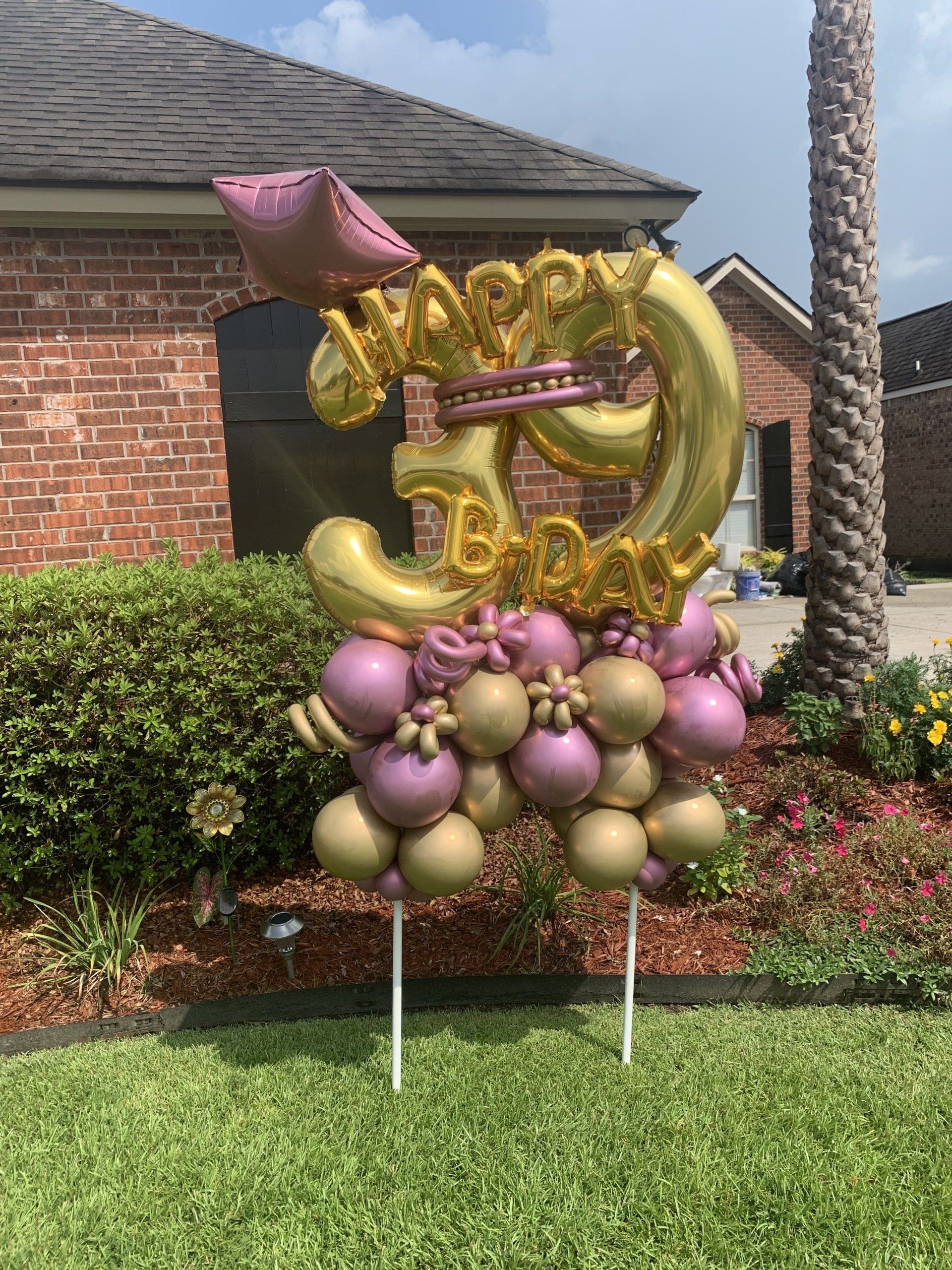 A bunch of balloons are sitting on top of a lawn in front of a house.