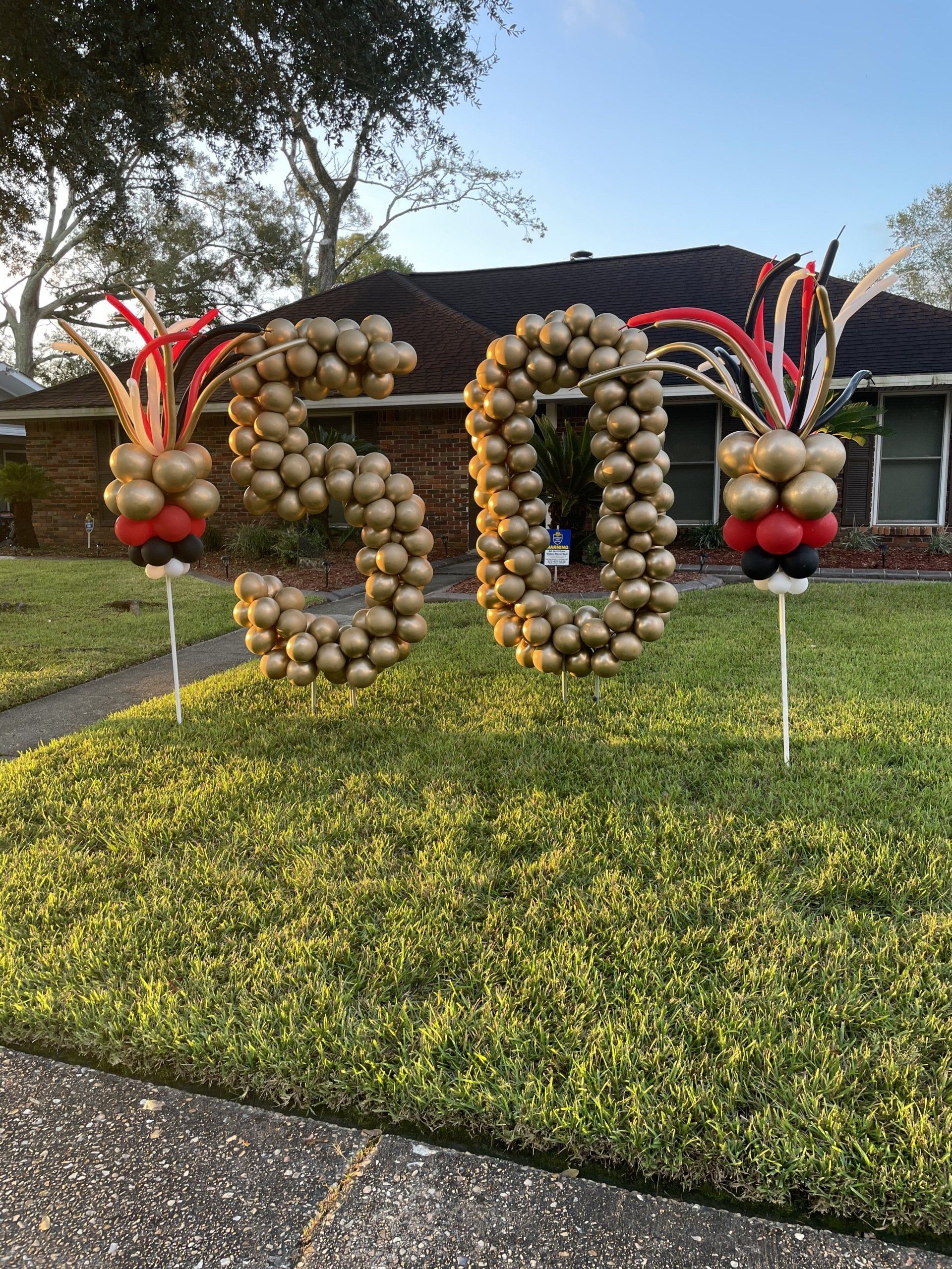 The number 50 is made out of balloons in front of a house.