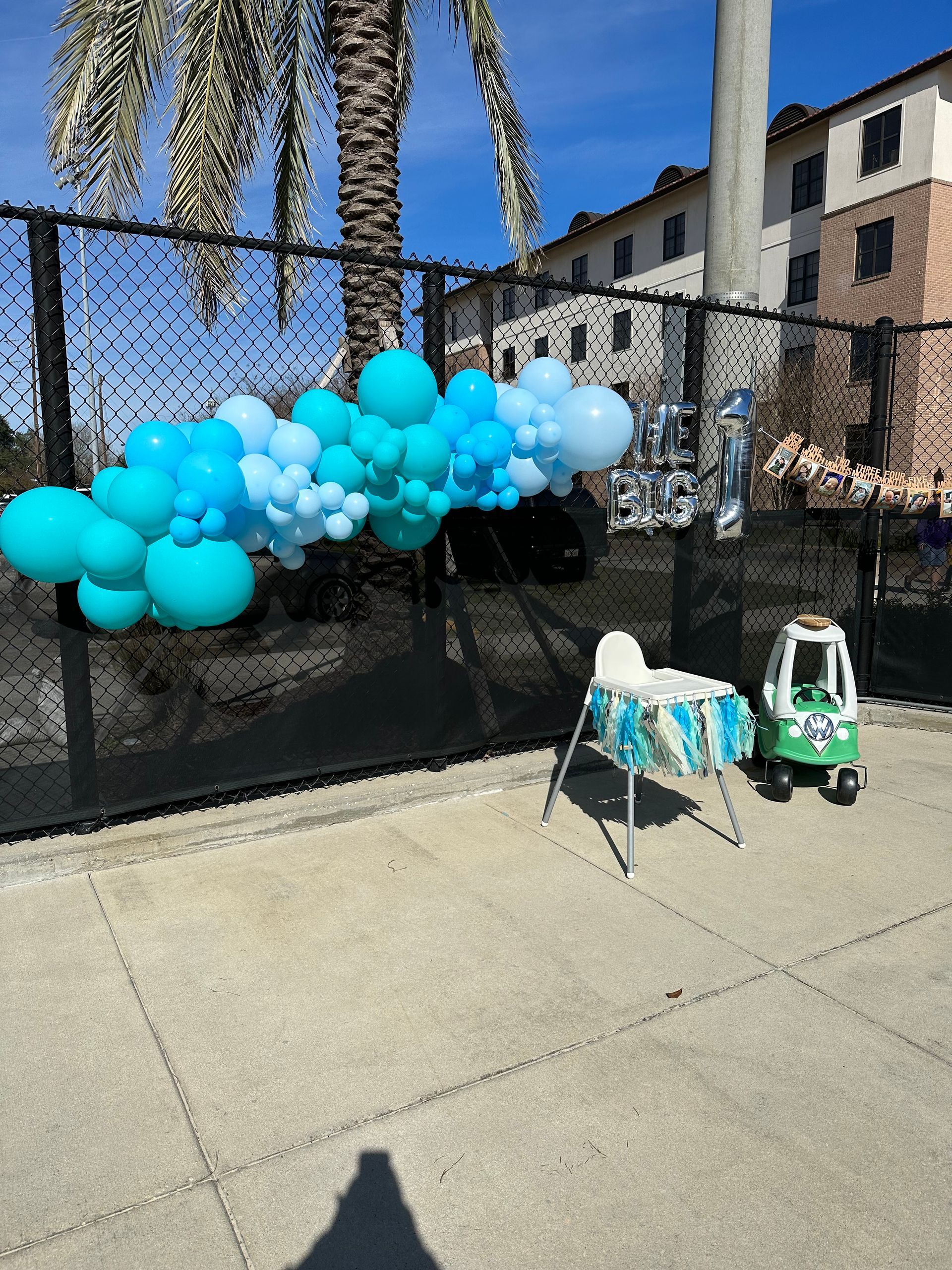 A fence with balloons and a high chair in front of it