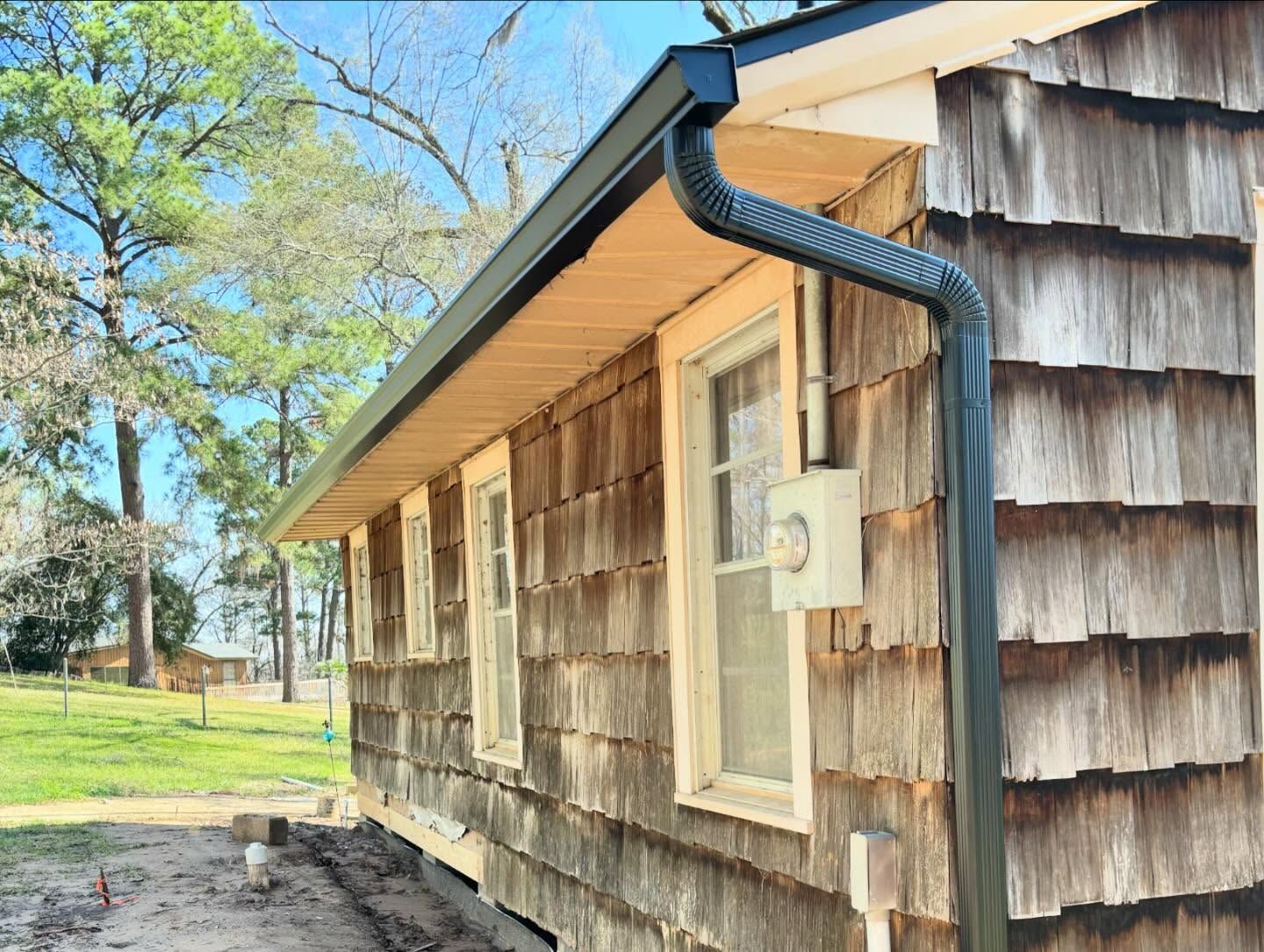 The side of a house with wooden siding and a black gutter.