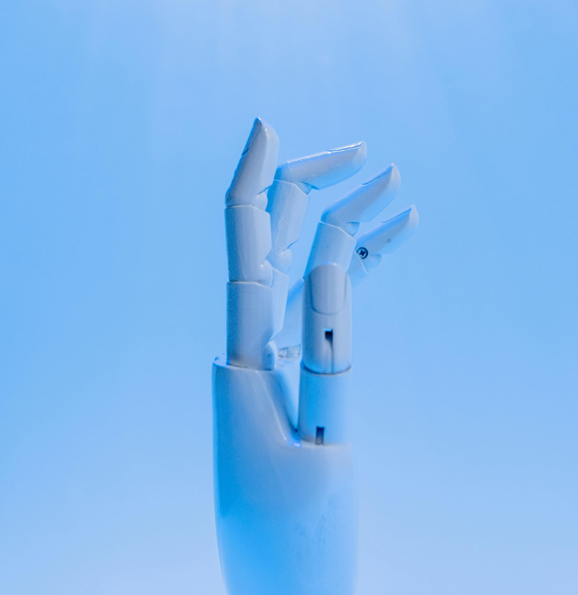 Witte robothand met licht gebogen vingers, tegen een blauwe achtergrond.