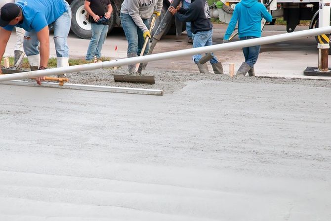 Team of workers screeding a large concrete foundation.