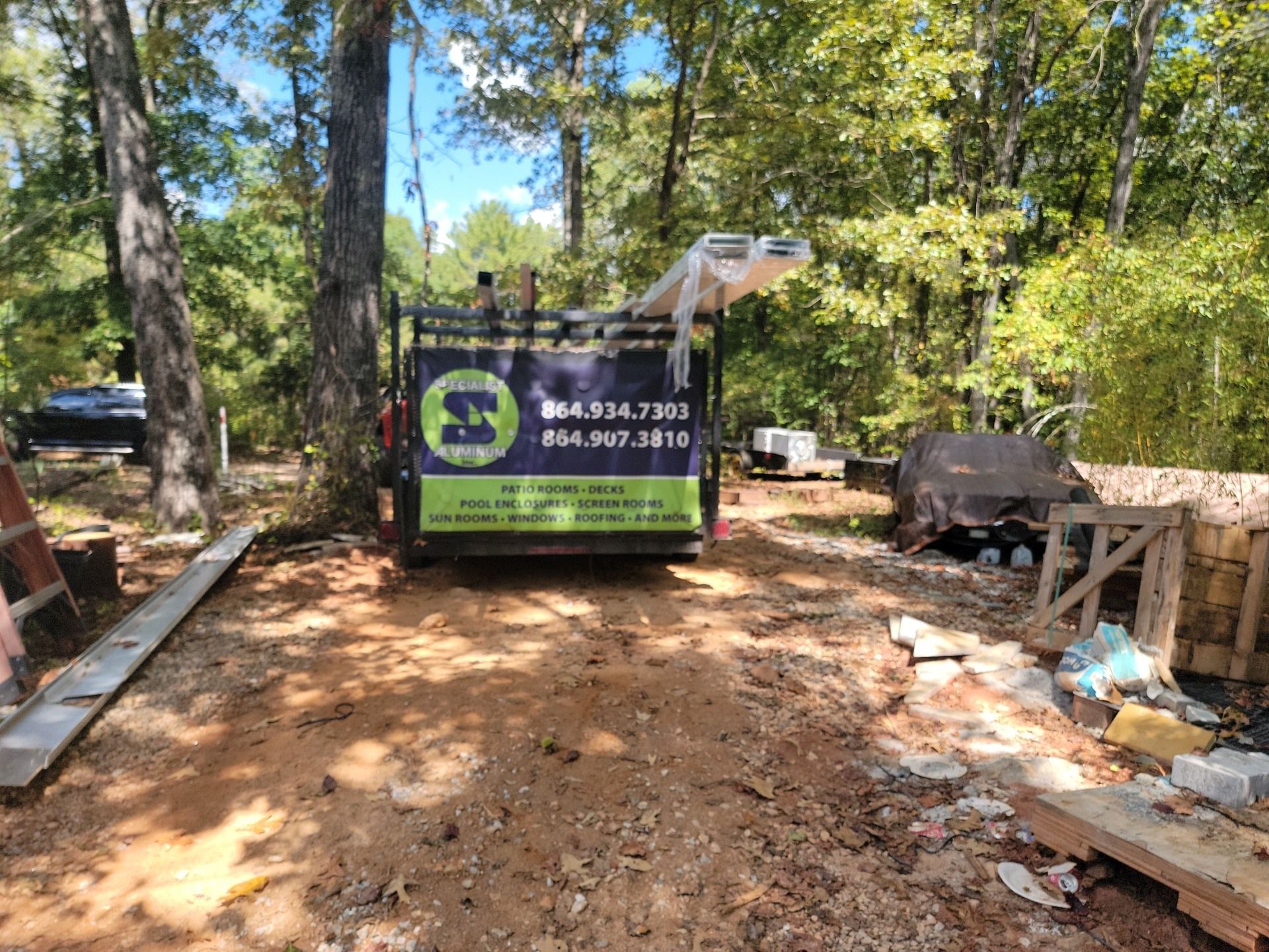 A dumpster is parked in the middle of a dirt road in the woods.