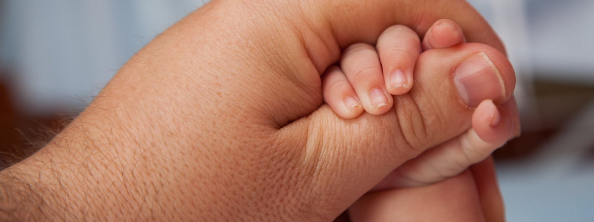 Newborn baby holding a parent’s finger, close connection and bonding moment
