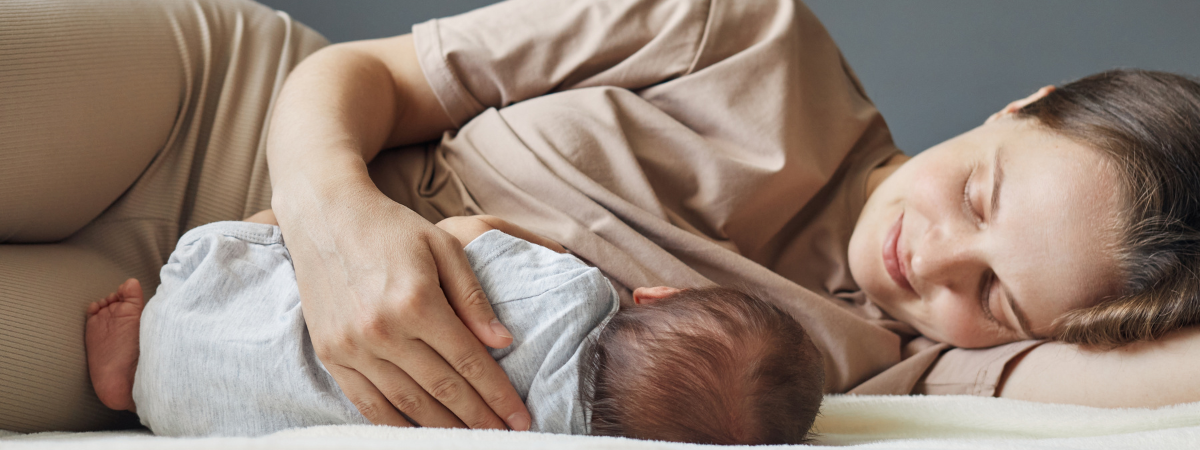 Mother resting with newborn baby in a calm postpartum moment at home