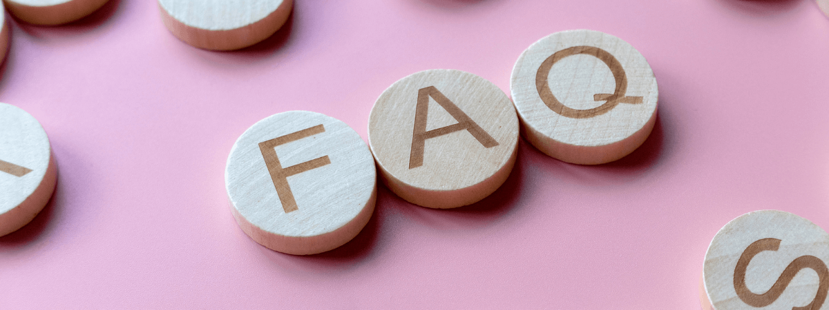 Wooden blocks spelling out FAQ on a pink background