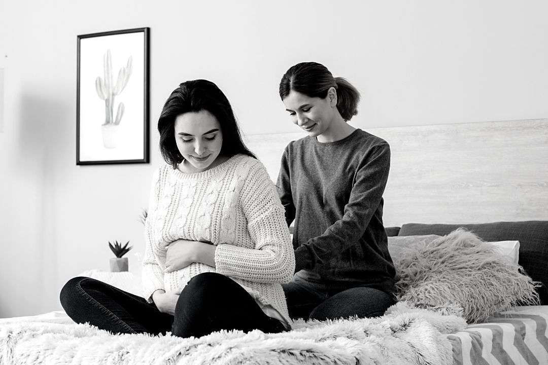 Doula Supporting Pregnant Woman A doula providing massage support to a pregnant woman in a calm, home setting. Doula care for pregnancy. – what’s a doula?
