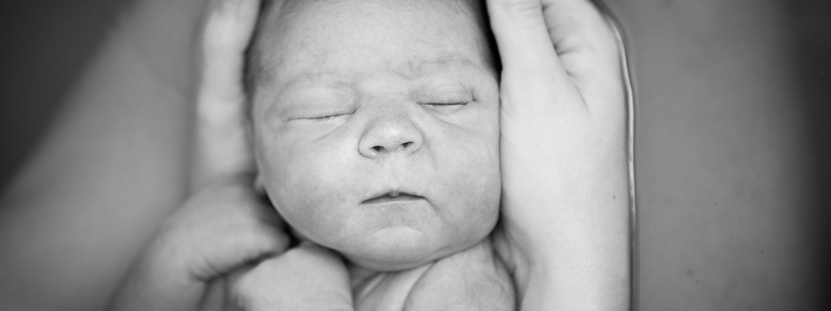 Close-up black and white photo of a newborn baby sleeping peacefully