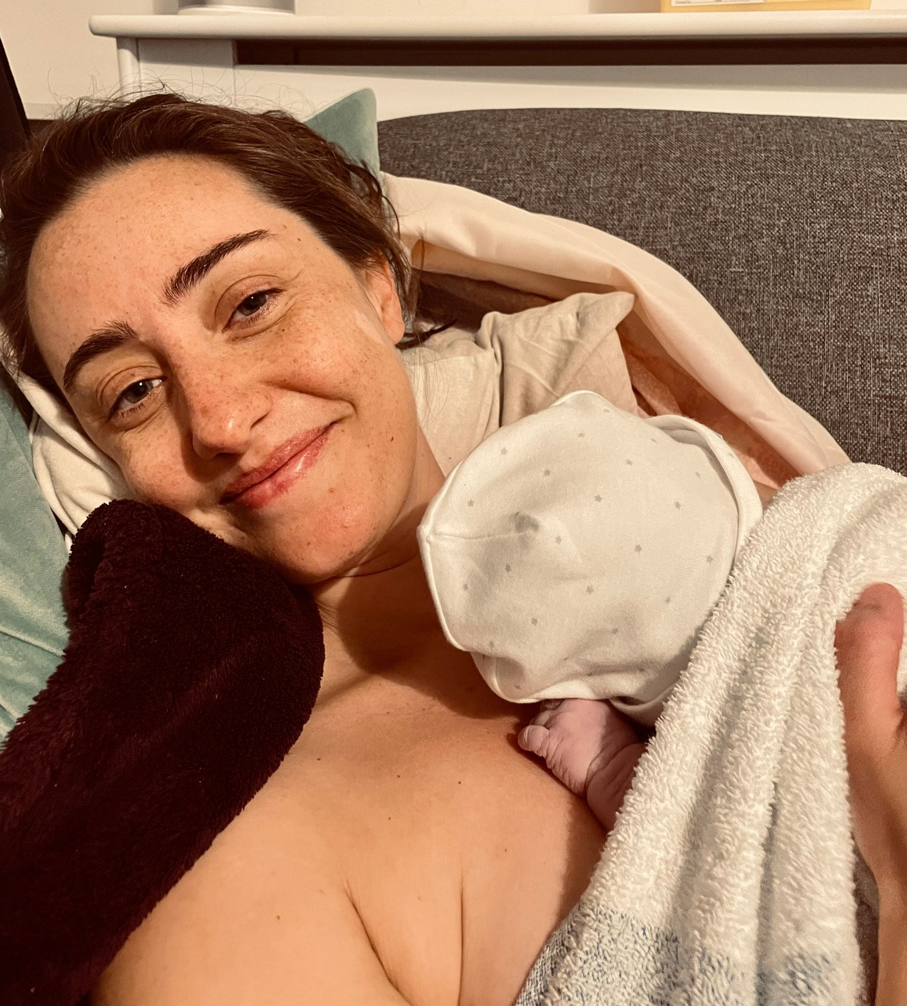 New mother cuddling her baby at home after a positive birth story