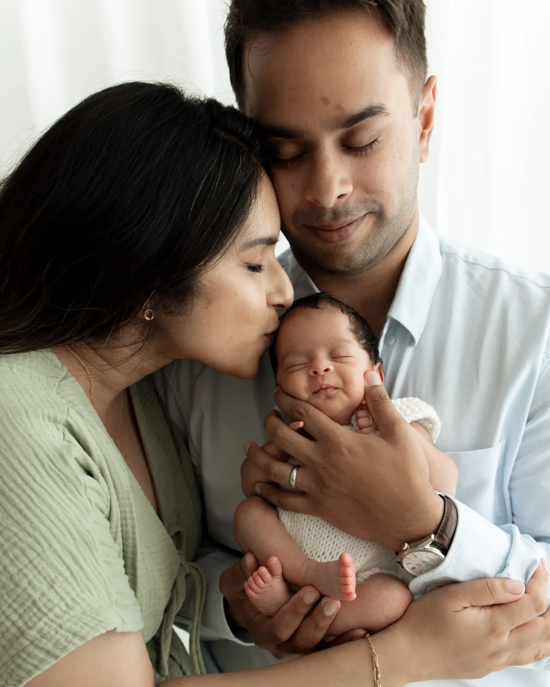Parents holding their newborn during a photography shoot near Wimbledon