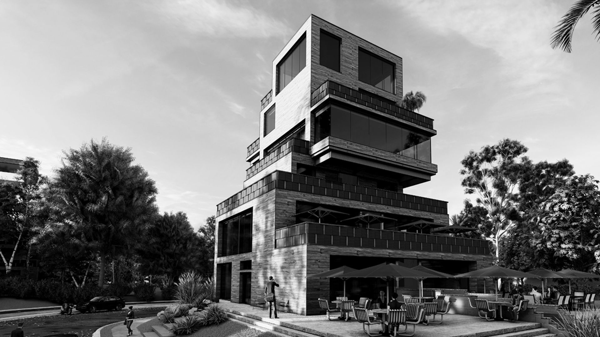 A modern, multi-story building with stacked, cantilevered levels and large windows, surrounded by trees and a patio area.