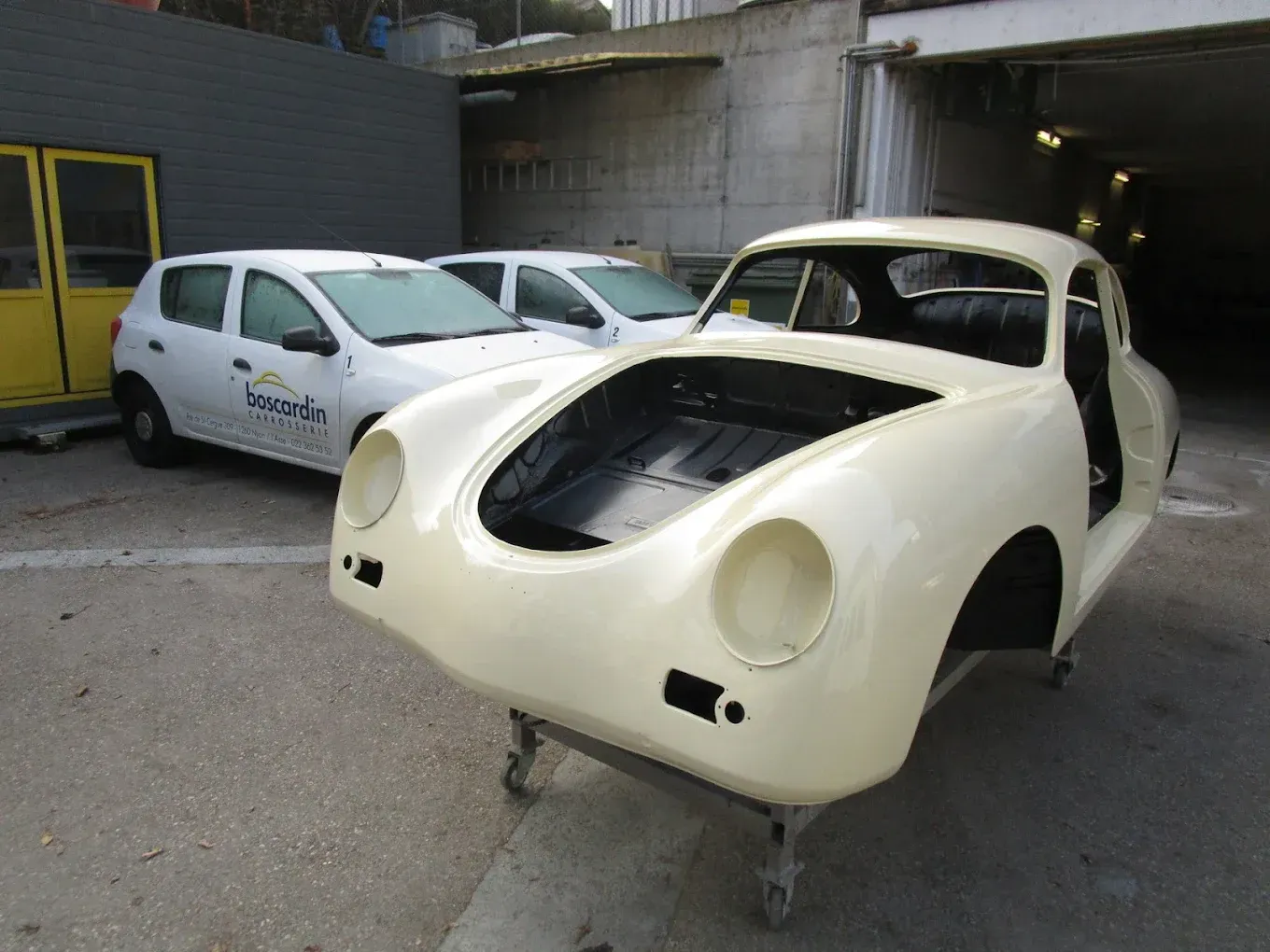 Une voiture blanche avec le capot relevé est garée sur un parking