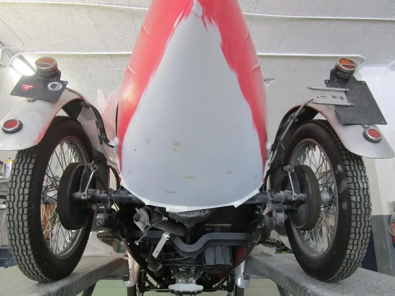 Une moto rouge et blanche est exposée dans un garage