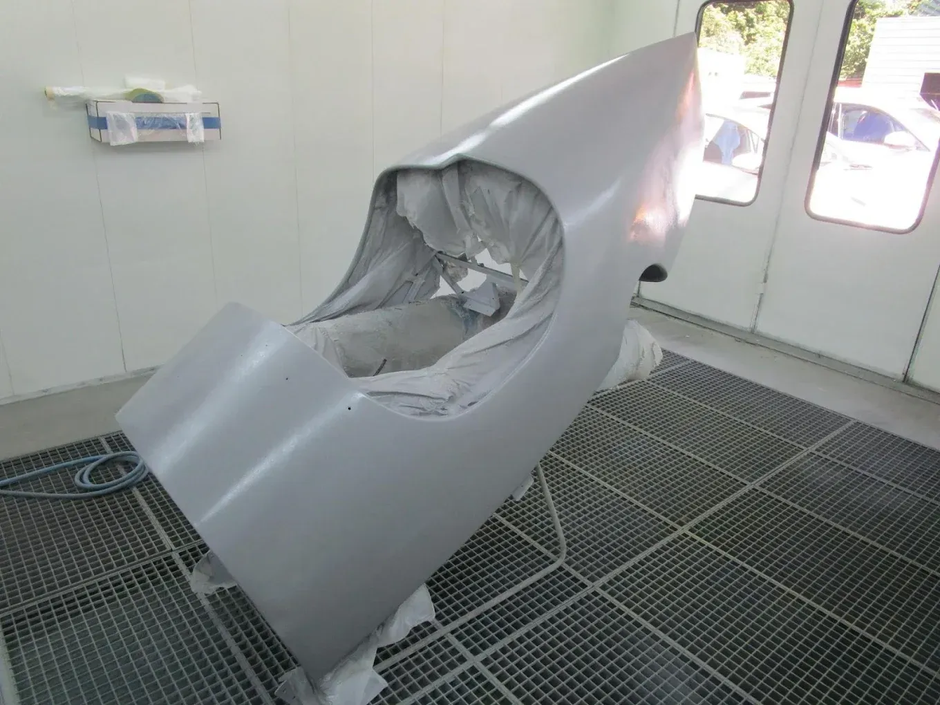 Un gros morceau de métal se trouve dans une cabine de peinture.