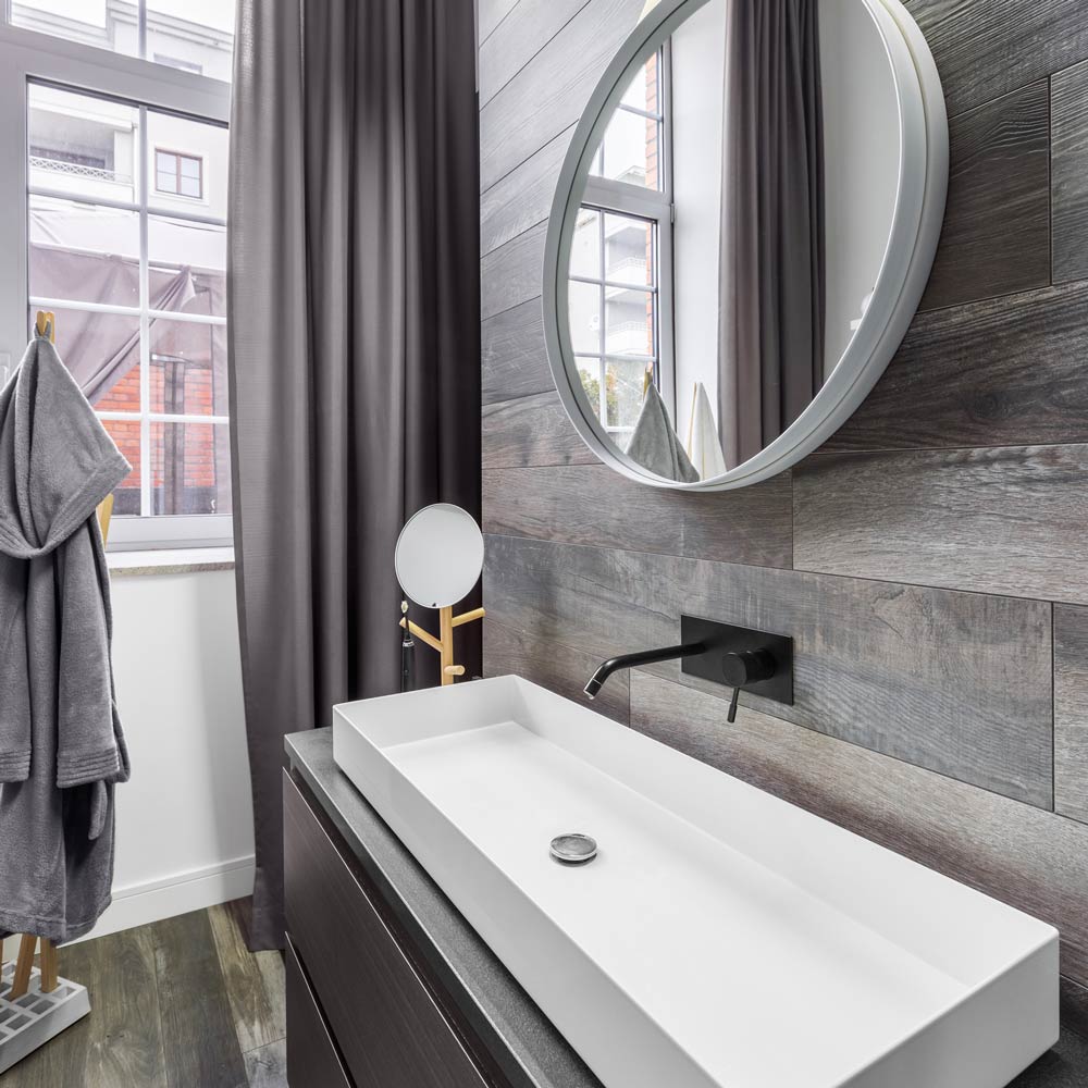 a bathroom with a large sink and a round mirror