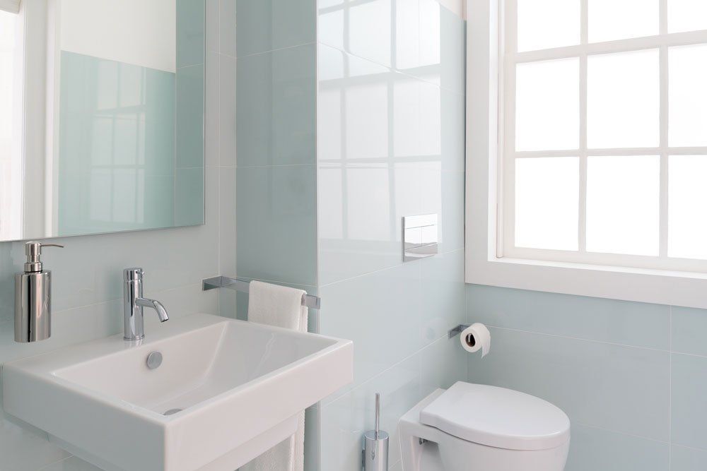 a bathroom with a sink , toilet , mirror and window .
