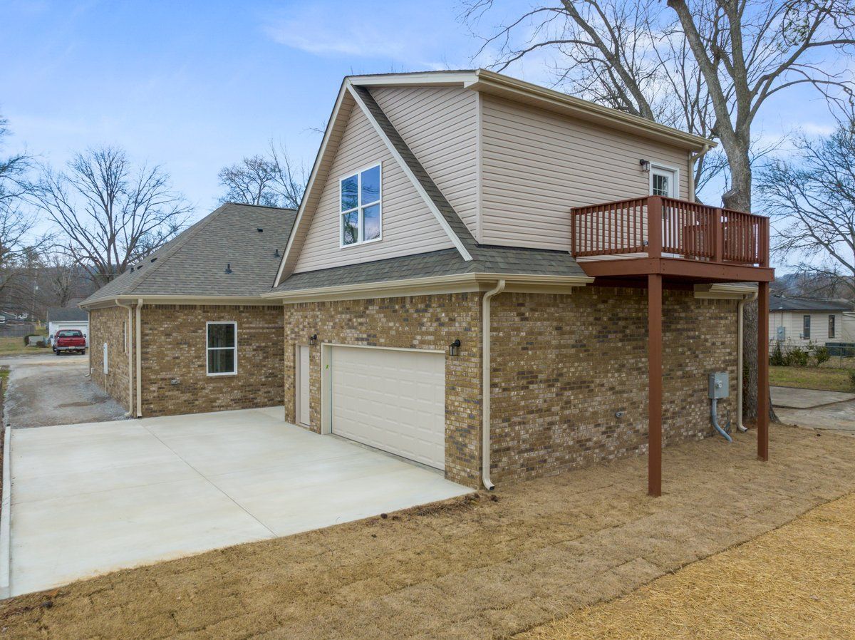 Rear view of a completed Mims Custom Home Construction build — showing garage, concrete driveway, upper-level deck.r