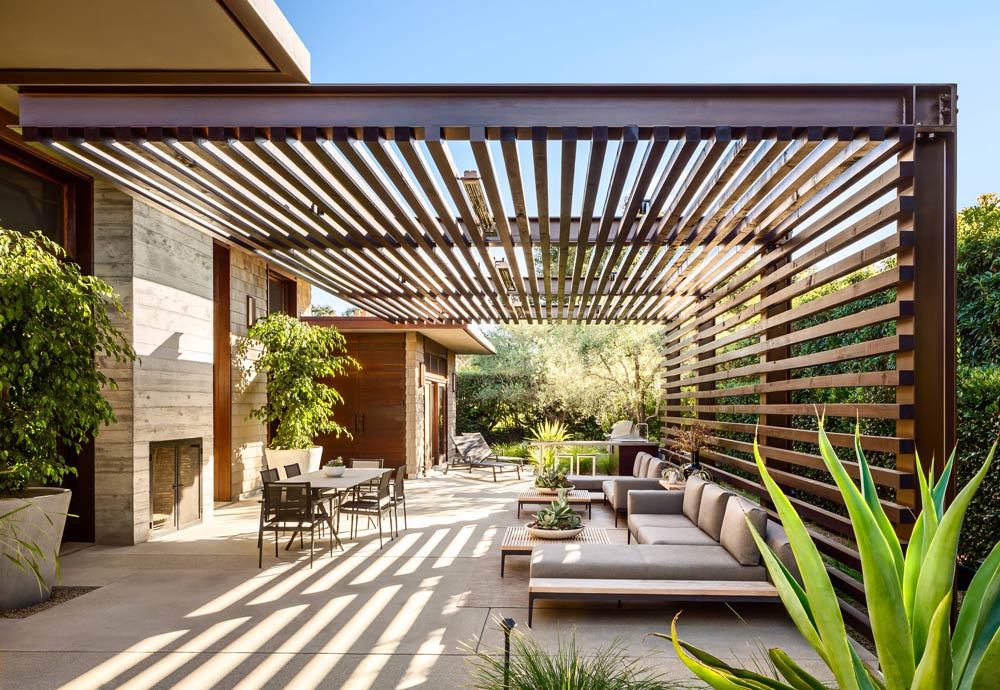 a patio with a pergola and a couch underneath it .