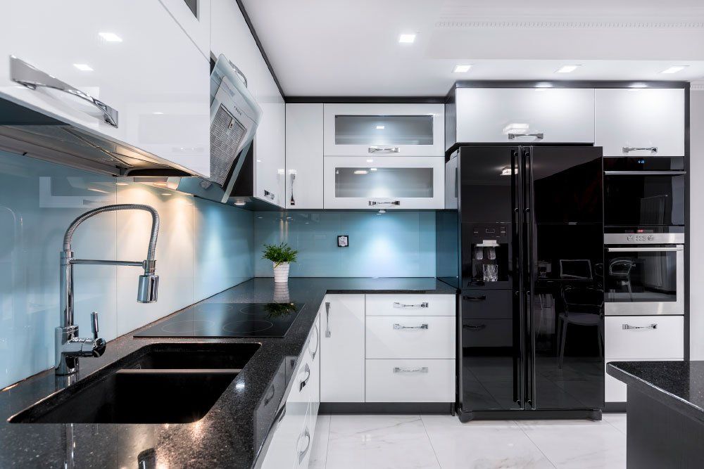 a kitchen with black and white cabinets , a black refrigerator , a sink , and a faucet .