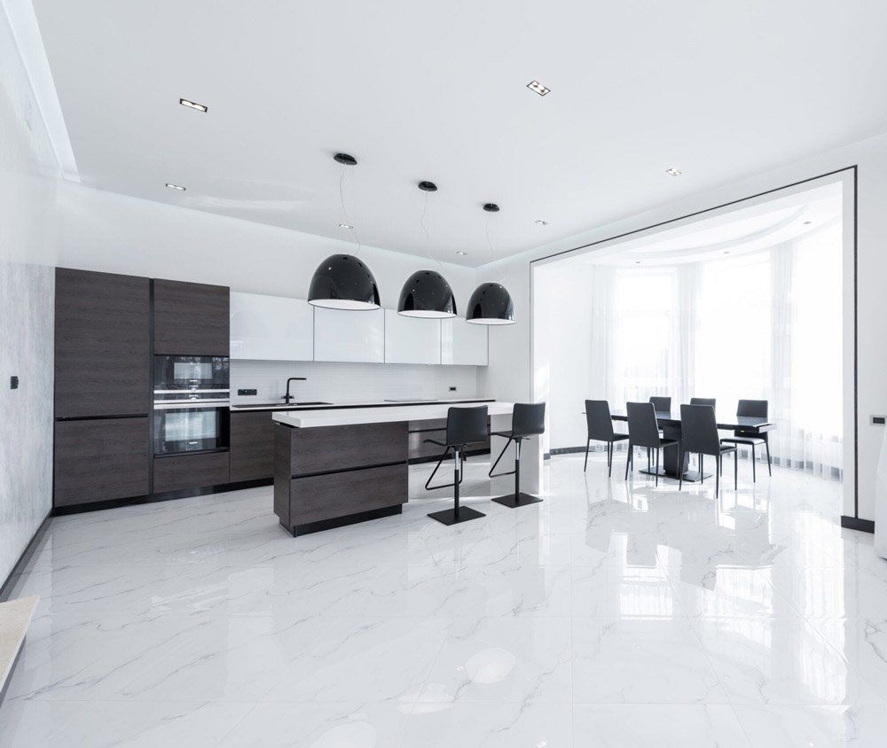 a black and white kitchen with a dining room in the background .