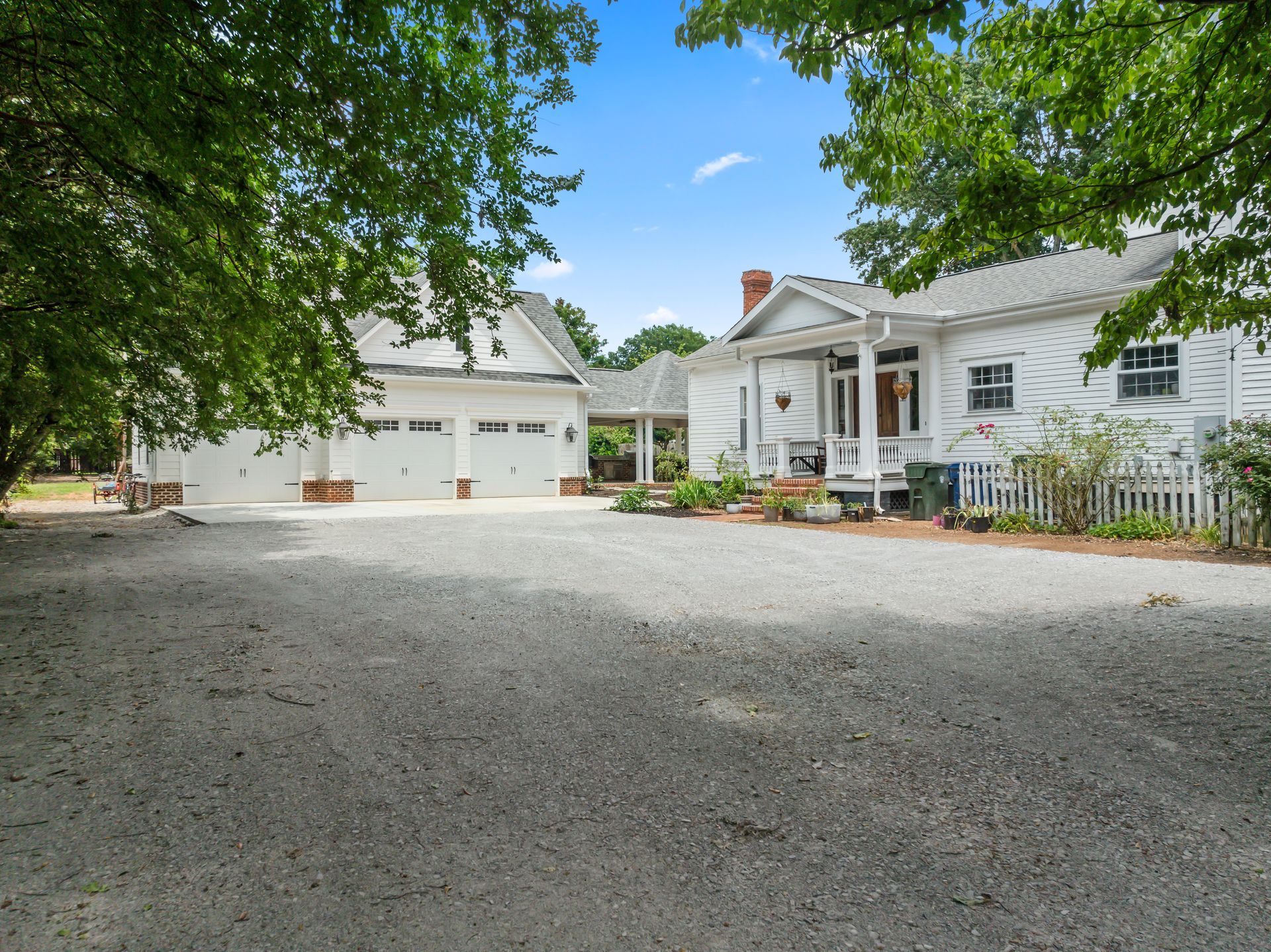 A large white house with a gravel driveway in front of it