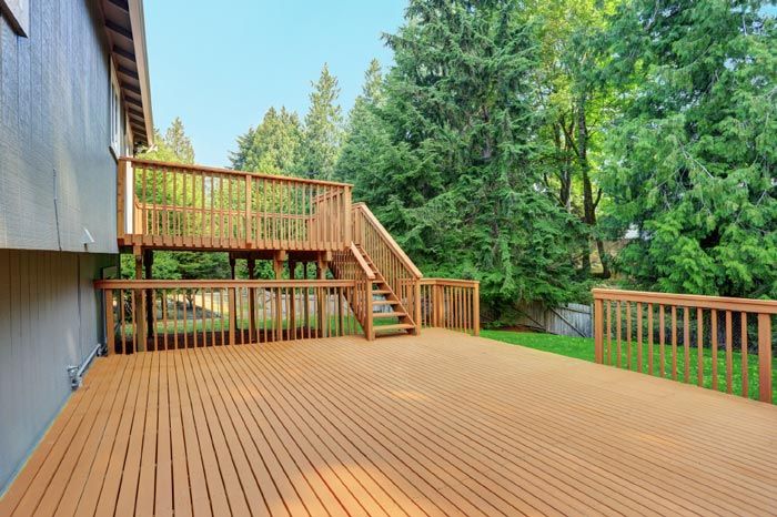 a large wooden deck with stairs leading up to it is in the backyard of a house .