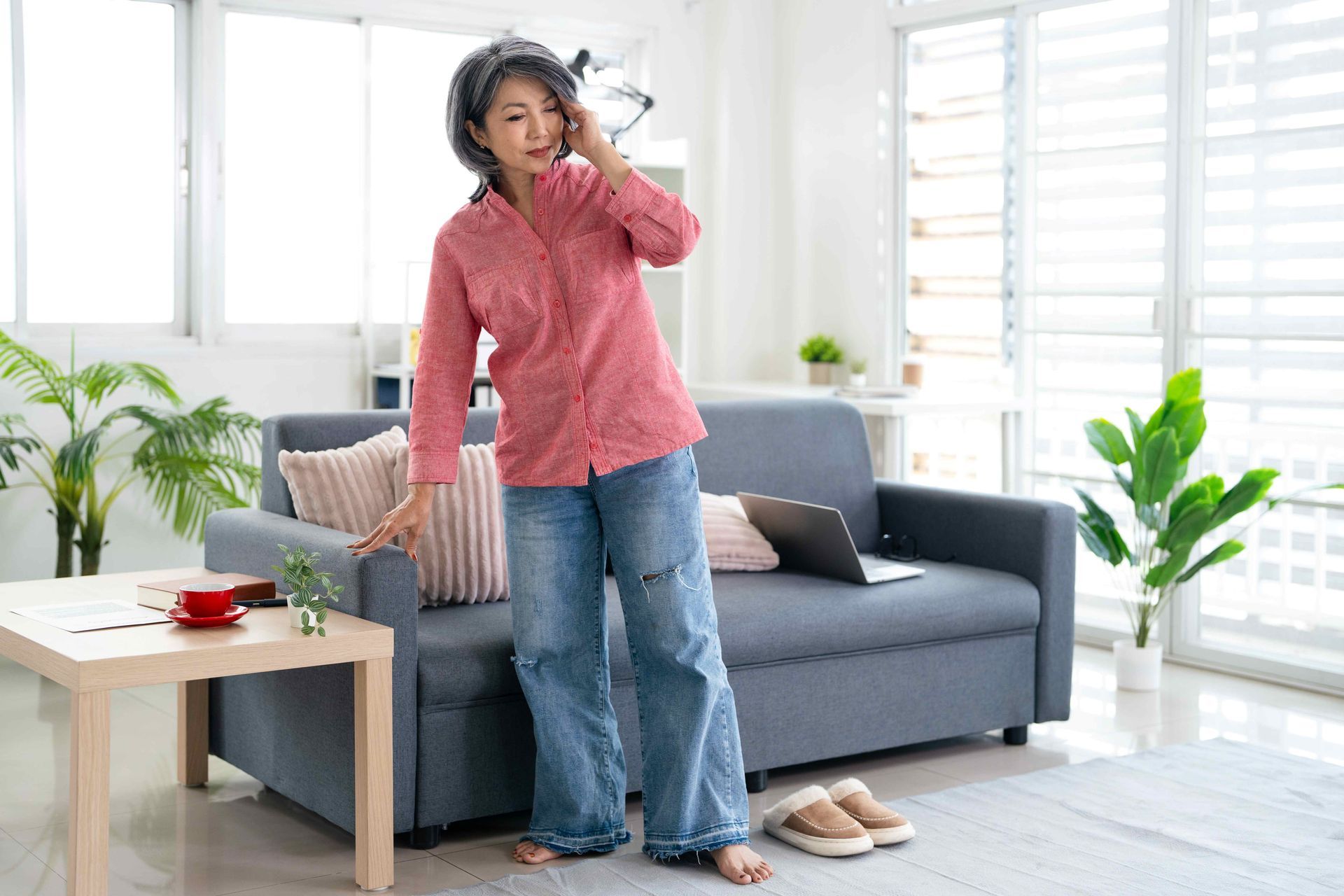 A woman suffering a dizzy spell standing in her living room.