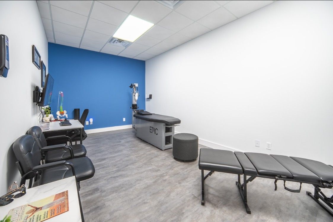Physical therapy room with blue accent wall, treatment table, exercise bike, and chairs