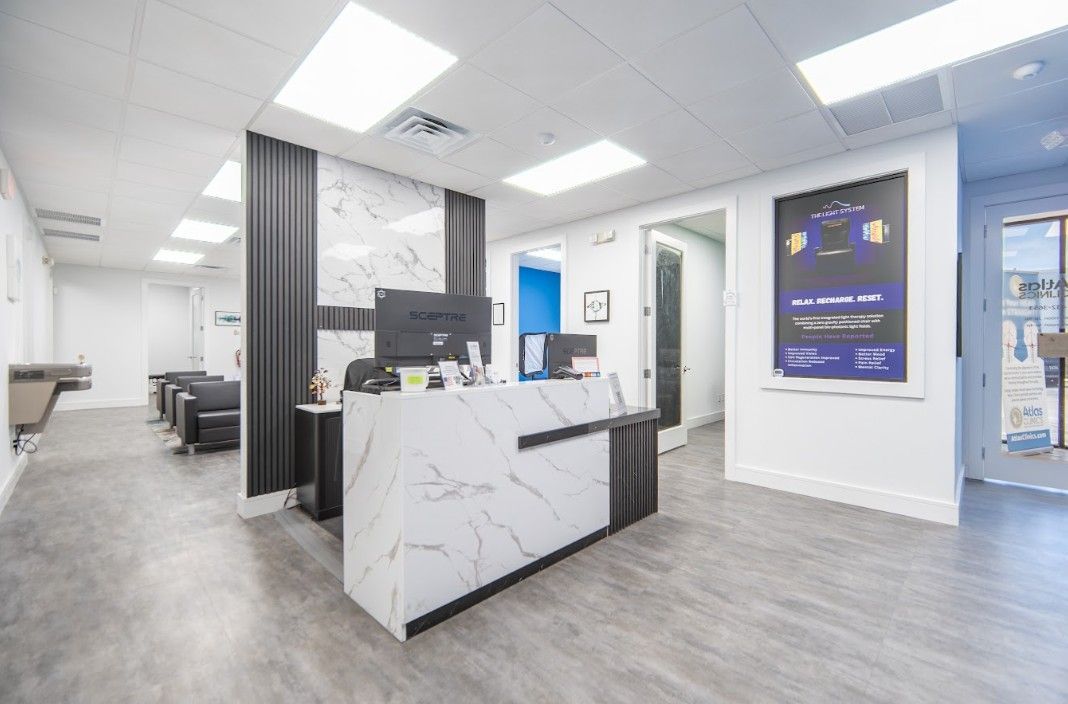 Modern office reception area with white marble desk, gray flooring, blue wall art, and bright overhead lighting